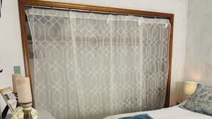 A bedroom with a bed, a bedside table, a lamp, and a curtain with a geometric pattern. - WELCOME to Pirates Harbor! Crab, fish & relax. Rare private boat launch  & hoist (Slidell)