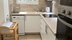 Een kleine keuken met een vaatwasser, een spoelbak, een raam met gezandstraald glas en een inbouwoven.