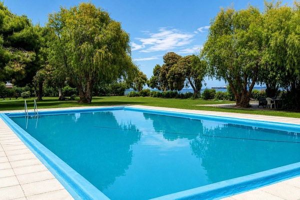 The shared pool sits among mature trees and open lawns, offering a peaceful place to cool off between beach visits while enjoying the greenery that surrounds the complex.