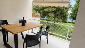 Een balkon met een houten tafel en stoelen, een fles en een bloempot.