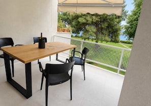 Ein Balkon mit Holztisch und -stühlen, einer Flasche und einem Blumentopf.