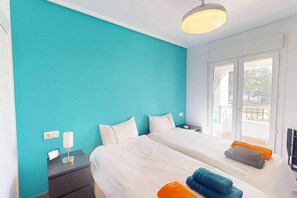 Ein Zimmer mit zwei Betten, einem Nachttisch, einer Lampe, einem Fernseher und einem Fenster mit Blick.