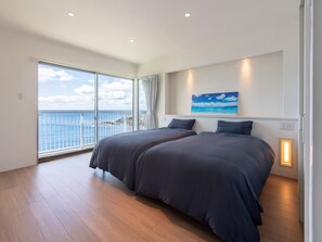 A bedroom with two beds, a large window with a view of the sea, and a painting on the wall. - Private Villa Kai -KUMANO- Have the sky and the sea all to yourself. That's the only luxury. (Shirahama-cho)