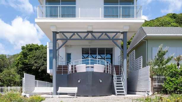 A two-story building with a balcony, a staircase, and a pool area.