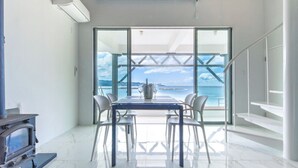 Un intérieur moderne avec une grande fenêtre, une table à manger, des chaises et une cheminée.