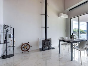 Un intérieur moderne avec une cheminée, un coin repas et une vue sur l’extérieur.