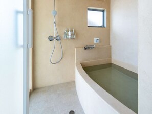 Une salle de bain moderne avec une baignoire sur pieds, une douchette et une petite fenêtre.