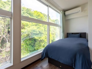 Une chambre avec une grande fenêtre, un lit et un appareil de climatisation.
