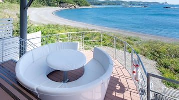 A deck with a circular seating area overlooking a beach and the sea.