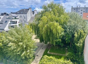 A residential area with modern buildings, a pathway, and lush greenery. - 10° Ouest - T3 renovated 2025 - Park view - Quiet street (Lorient)