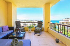 Ein Balkon mit zwei Stühlen, einem Sofa, einem kleinen Tisch und einem Blumentopf.