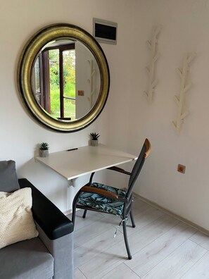 A room with a white desk, a chair with a leaf-patterned cushion, a round mirror, and a small potted plant. - Mreznica - Zelena oaza I (Generalski Stol)
