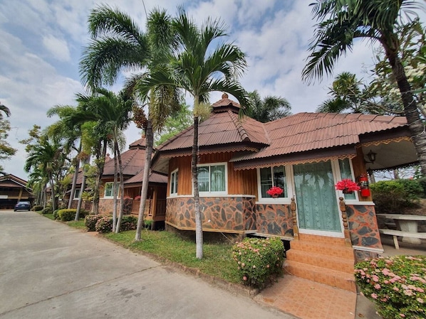Una hilera de casas tipo bungalow con tejados de tejas, rodeadas de palmeras y follaje.