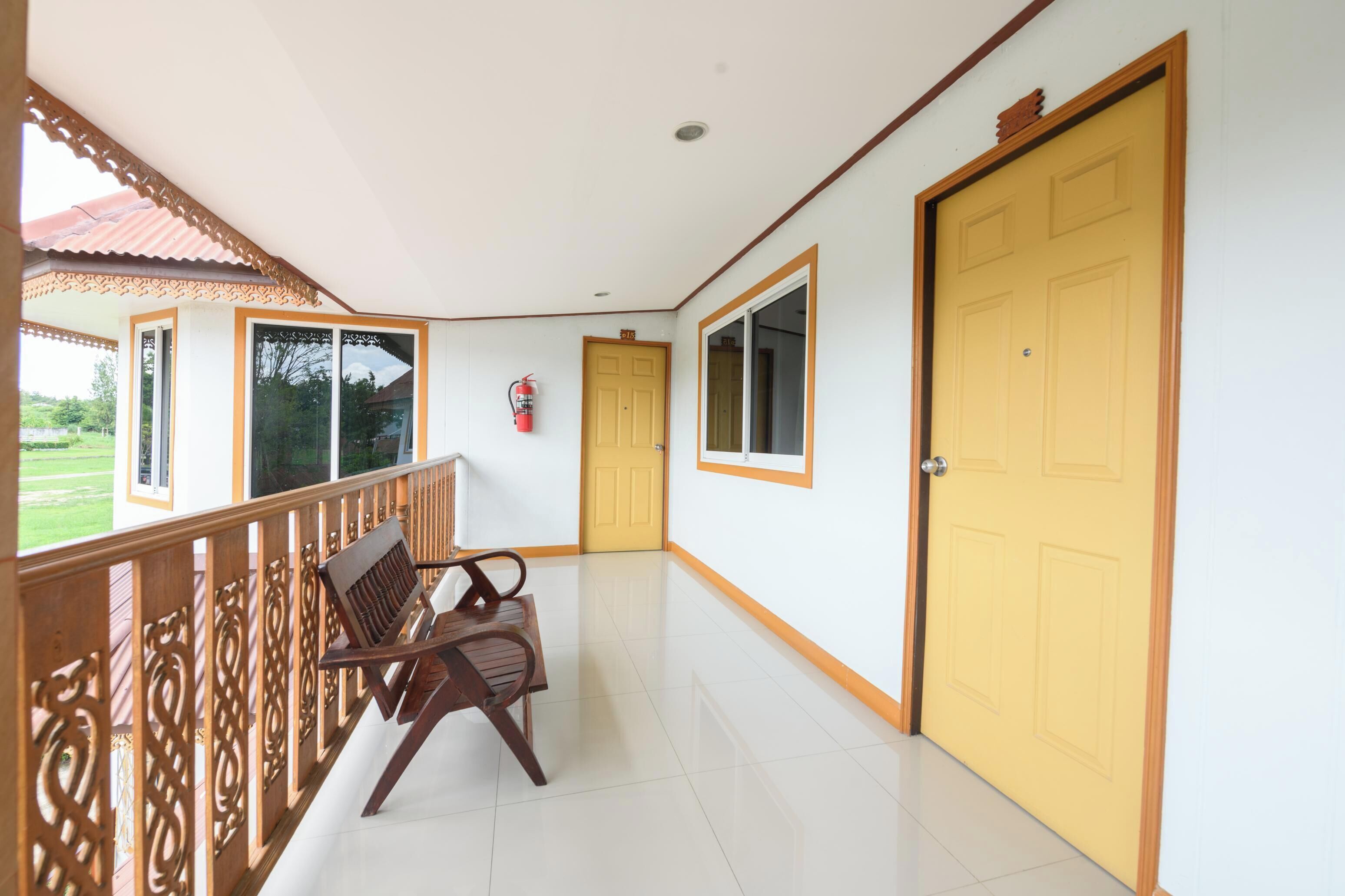 A corridor with a bench, a yellow door, and a window.