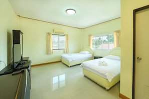 Una habitación de hotel con dos camas, un escritorio con computadora, aire acondicionado y una ventana con cortinas.