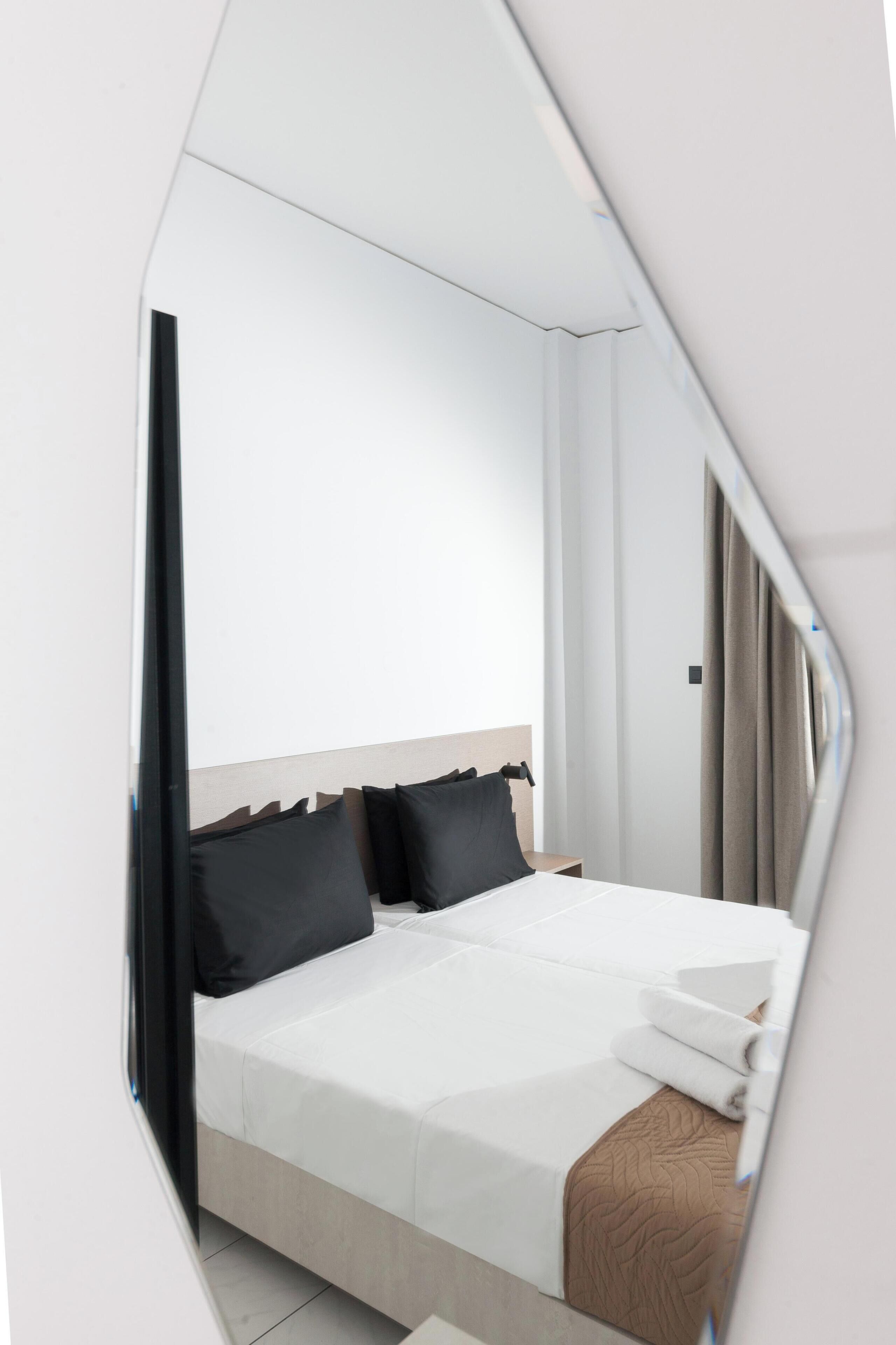 Een moderne hotelkamer met een bed, een spiegel en een raam.