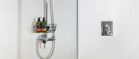 A shower with a handheld showerhead, a wall-mounted faucet, and a chrome shower tray.