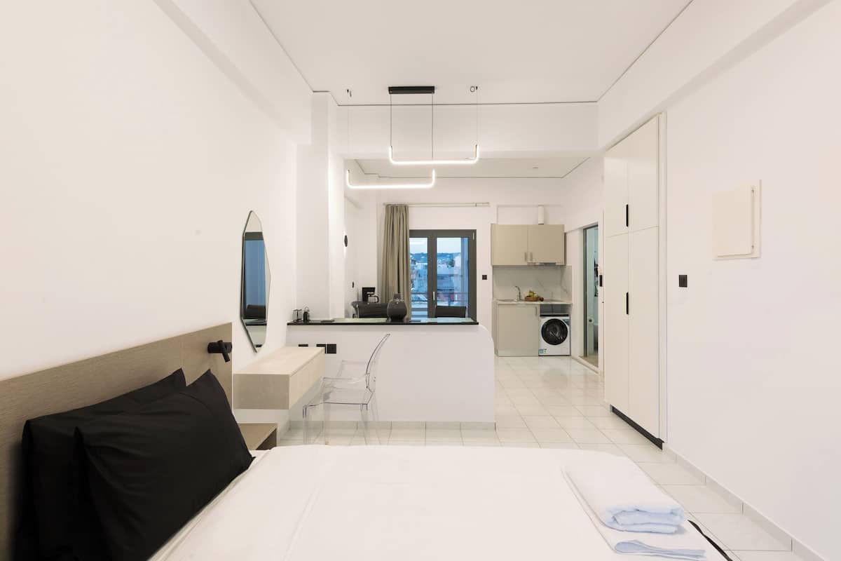 Habitació d'hotel moderna amb un llit, una cuineta petita, una rentadora i vistes a la ciutat.