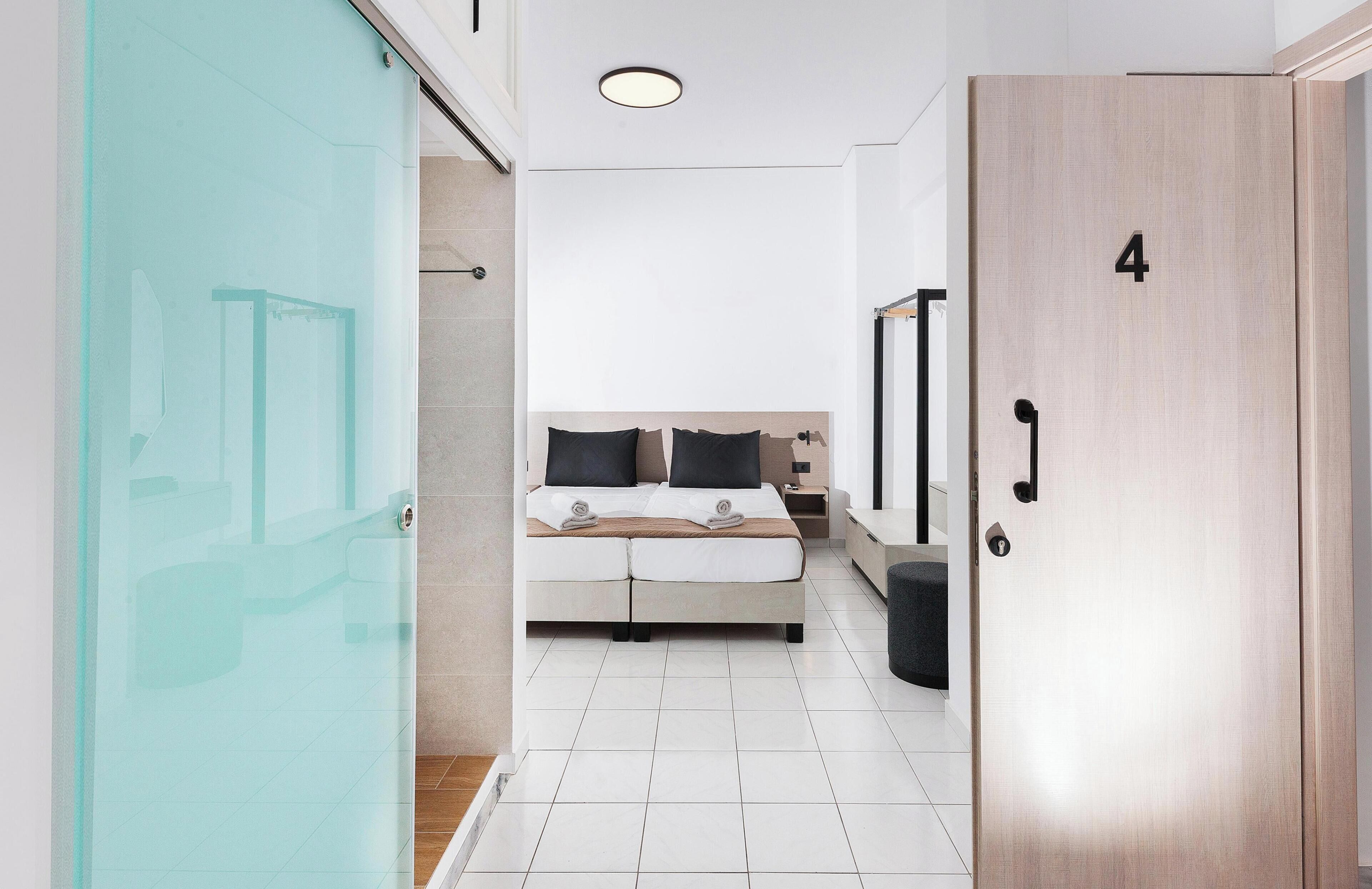Una camera d'albergo con un letto, un comodino, un armadio e una porta in vetro.