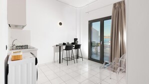 A modern kitchen with a gas stove, a coffee machine, and a dining area with two chairs.