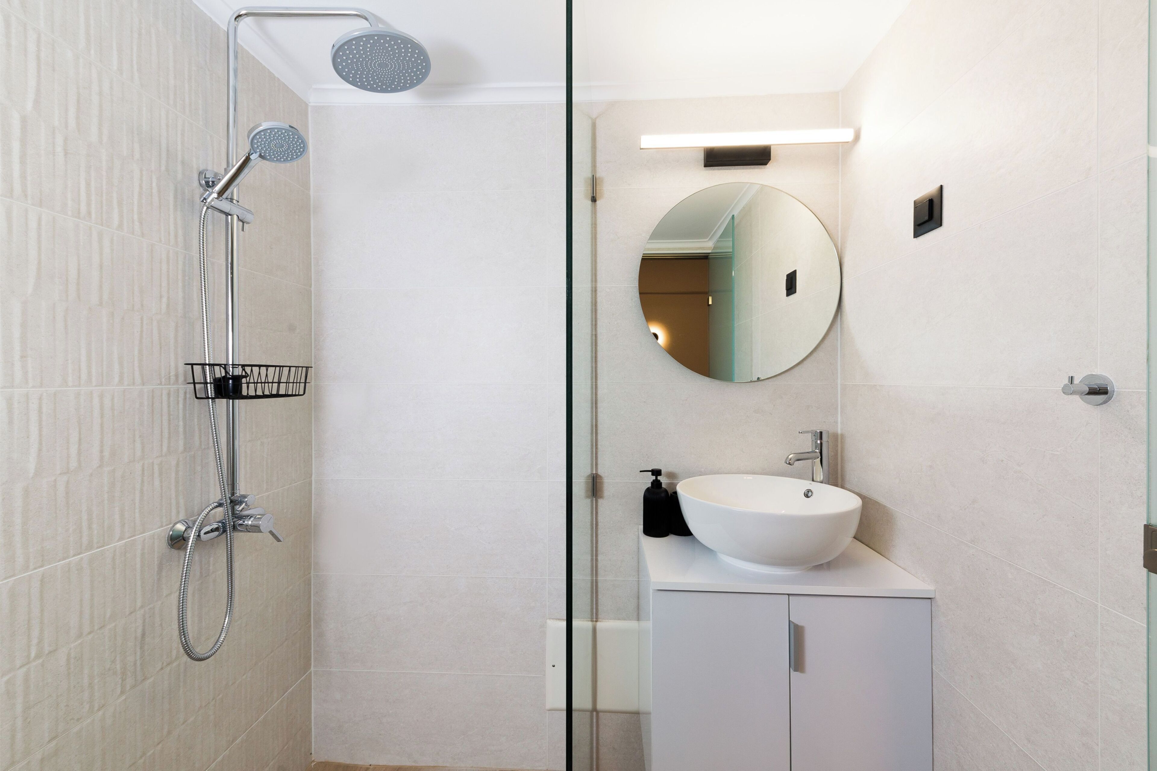 Ein modernes Badezimmer mit Dusche, Waschbecken, Spiegel und Schrank.