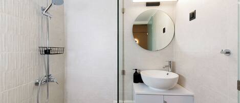 Ein modernes Badezimmer mit Dusche, Waschbecken, Spiegel und Schrank.