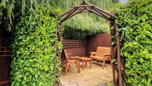 A wooden pergola with a bench and table in a garden. - The Kingfisher Falls (Melton Mowbray)