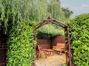 Une pergola en bois avec un banc et une table dans un jardin.
