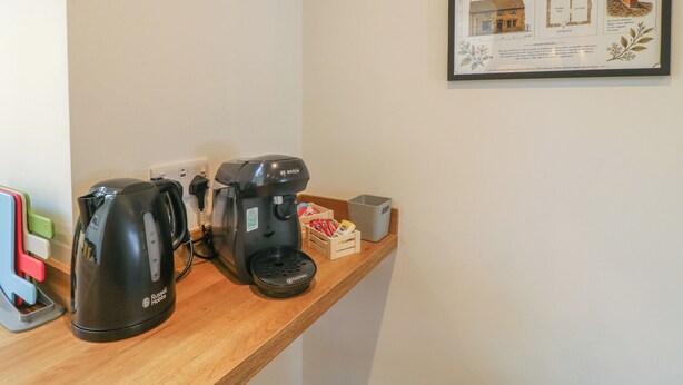 A coffee maker, a kettle, and a small box on a wooden shelf. - The Kingfisher Falls (Melton Mowbray)