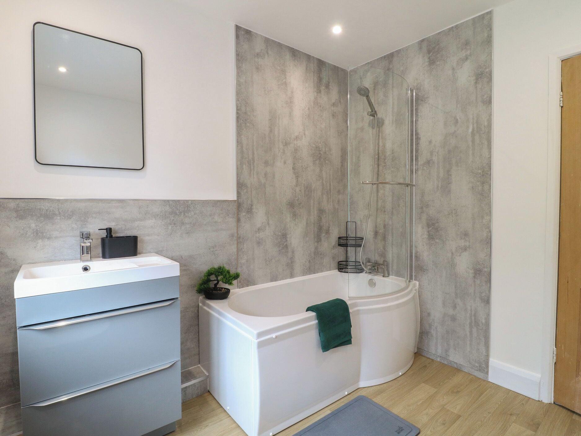 Une salle de bain moderne avec un lavabo blanc, des toilettes intégrées, une baignoire et un espace douche.