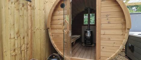 A wooden structure with a circular opening, a black heater inside, and a wicker basket outside.