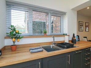 Cocina moderna con encimera de madera, pileta integrada y ventana con persianas.