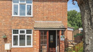 A brick building with a tiled roof, a front door, and a window with a white frame. - The Kingfisher Falls (Melton Mowbray)