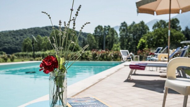 A clear view of a swimming pool with lounge chairs and a table with a book and flowers. - Houses in Stratola - Apartment 2 (Montella)