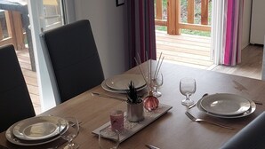 A dining table set for four with plates, cutlery, and glasses, a small plant, and a candle holder. - Mobile home Mimizan (Mimizan)