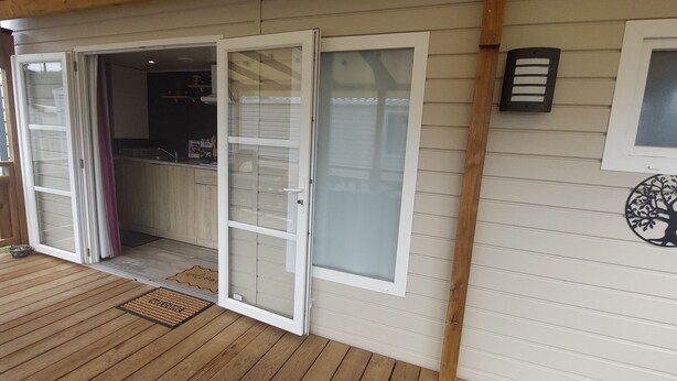 A wooden deck with a sliding glass door leading to a kitchen area. - Mobile home Mimizan (Mimizan)