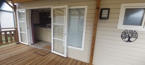 Une terrasse en bois avec une porte-fenêtre coulissante donnant sur un espace cuisine.
