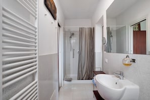 A bathroom with a shower, a sink, and a mirror.