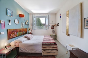 A bedroom with a bed, a window, and various wall decorations.