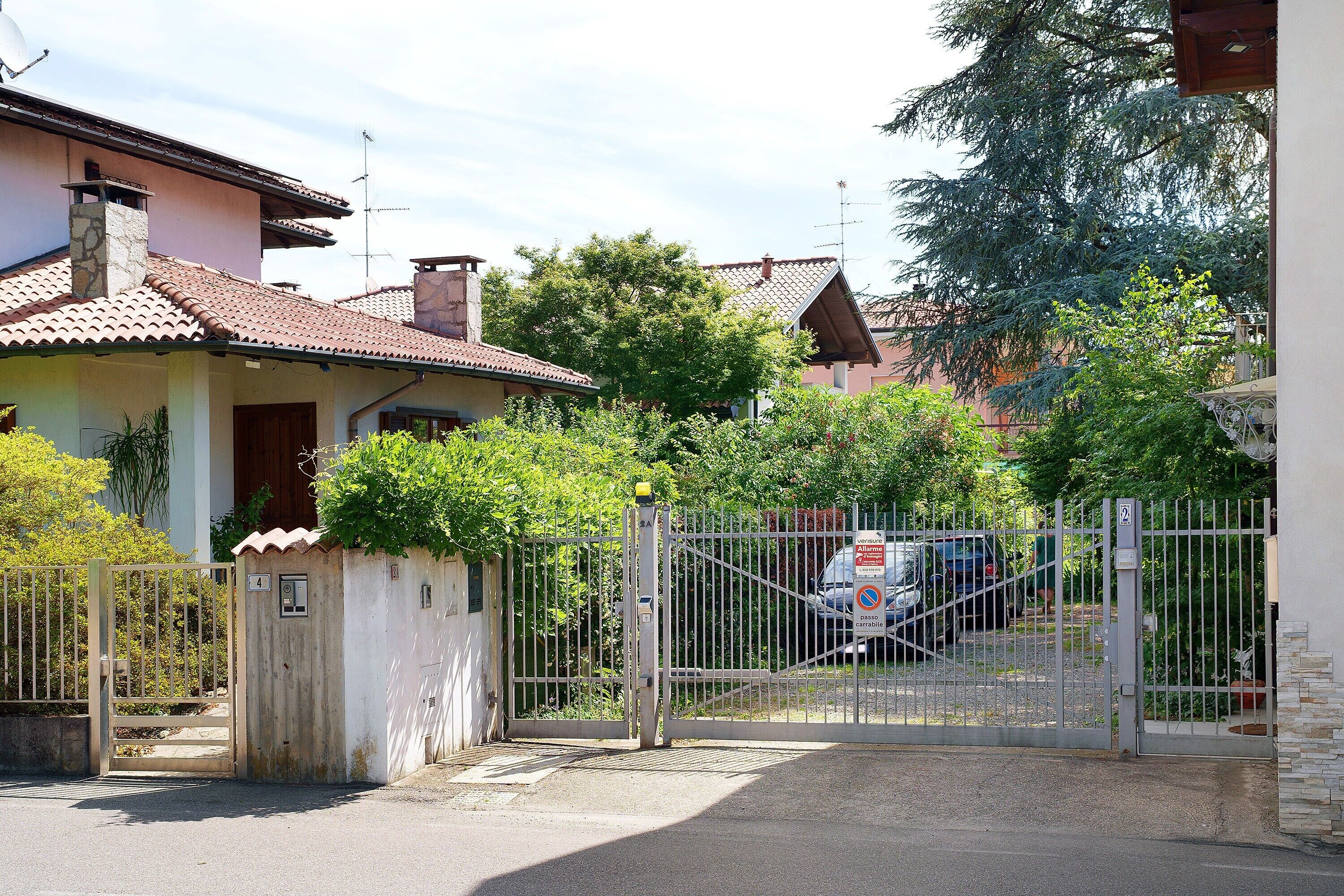 Un lotissement résidentiel fermé, avec une maison, un portail et une voiture garée.