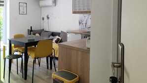A modern kitchen with a wooden countertop, a dining area with yellow chairs, and a visible trash bin. - City Oasis with Garden, BBQ, Pet-Friendly, near city center (Zagreb)