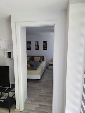 Un dormitorio con cama, escritorio y silla. Hay tres cuadros en la pared.