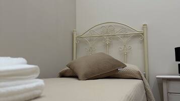 A neatly made bed with a headboard, a small bedside table, and a wall-mounted painting.