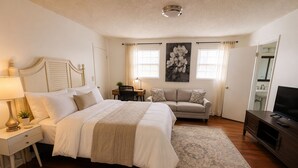 Ein Schlafzimmer mit Bett, Nachttisch, Lampe, Schreibtisch, Stuhl, Sofa, Fernsehschrank und Teppich.