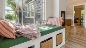 Een gezellige kamer met een groot raam, een openhaard en een groene, beklede bank.
