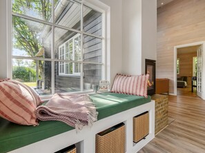 Ein gemütliches Zimmer mit einem großen Fenster, einem Kamin und einer gepolsterten grünen Bank.