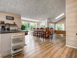 Eine geräumige Küche mit Essbereich, Holzboden und großen Fenstern.