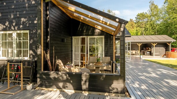 Een houten terras met buitenmeubilair, een overdekte patio en een garage.