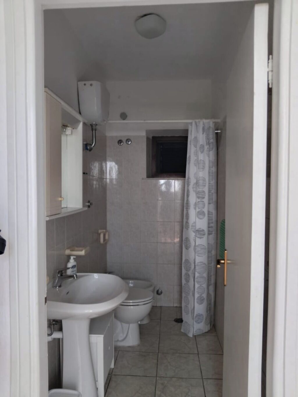 A small bathroom with a sink, toilet, and shower.