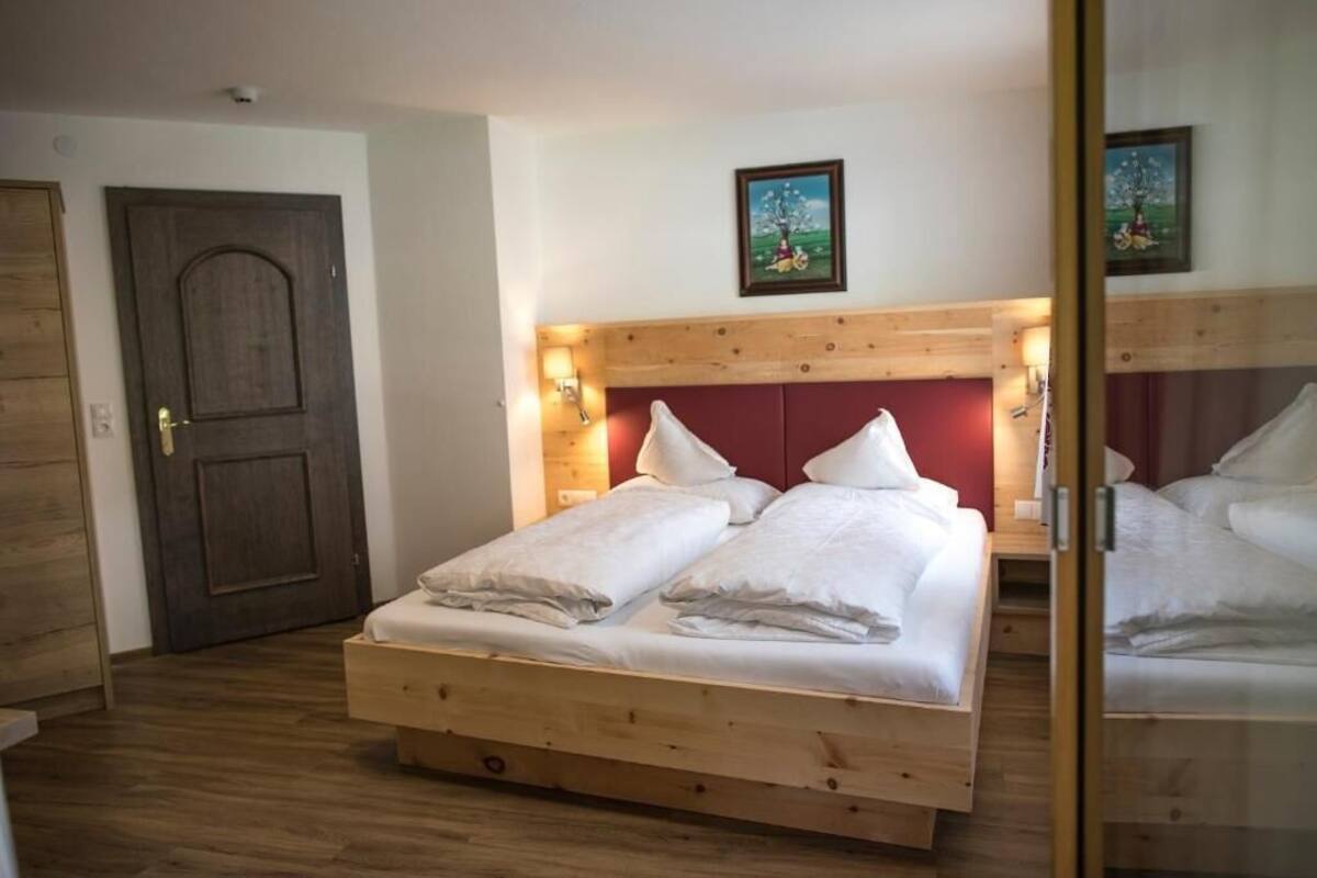 A wooden bed with white bedding, a wooden headboard, and a door with a picture above it.